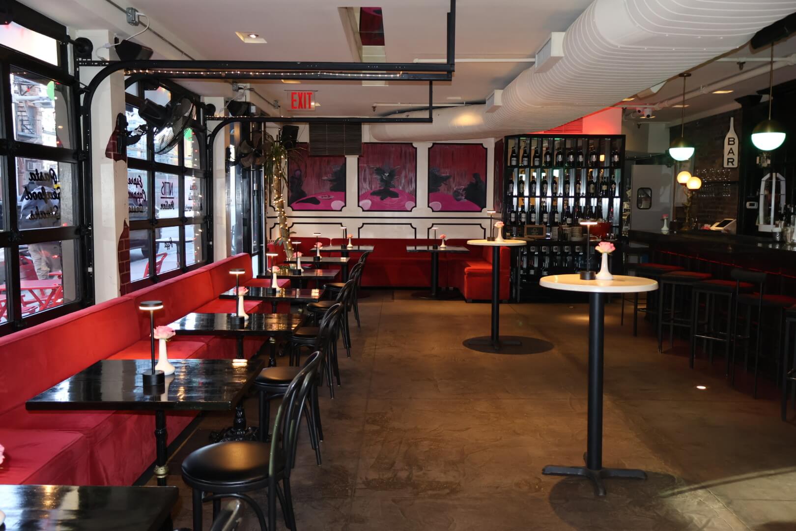 Black tables set against red booth with high tables in center of the room perfect for people to visit while mingling at an event
