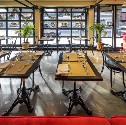 The interior of Nittis with red booths, large floor to ceiling garage windows and black table and chairs