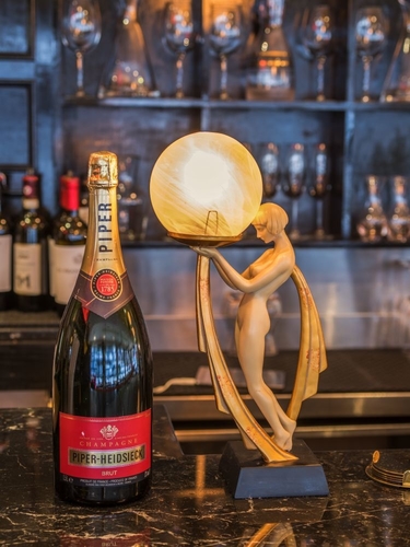 A bottle of Piper-Heidsieck on the bar with a small statue of a woman holding a light up orb