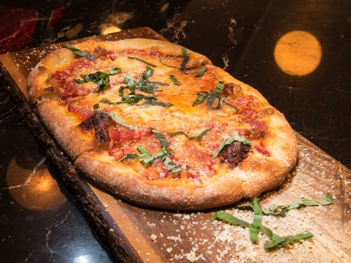 Margarita pizza on a wooden block on the black granit counter top