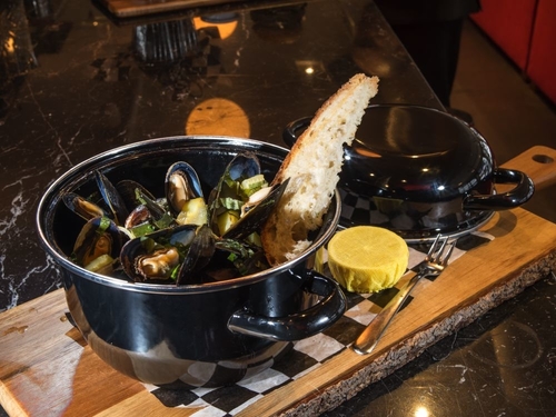 Mussels in a black top with bread and lemon