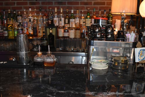 Nitti's black marble bartop with bottles of liquor against a brick wall