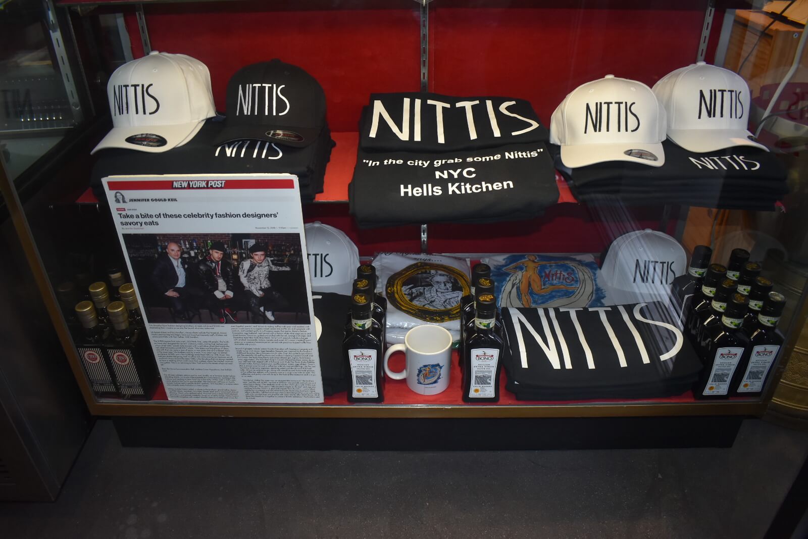 Nittis merch in a red display case showing black and white hats and tshirts