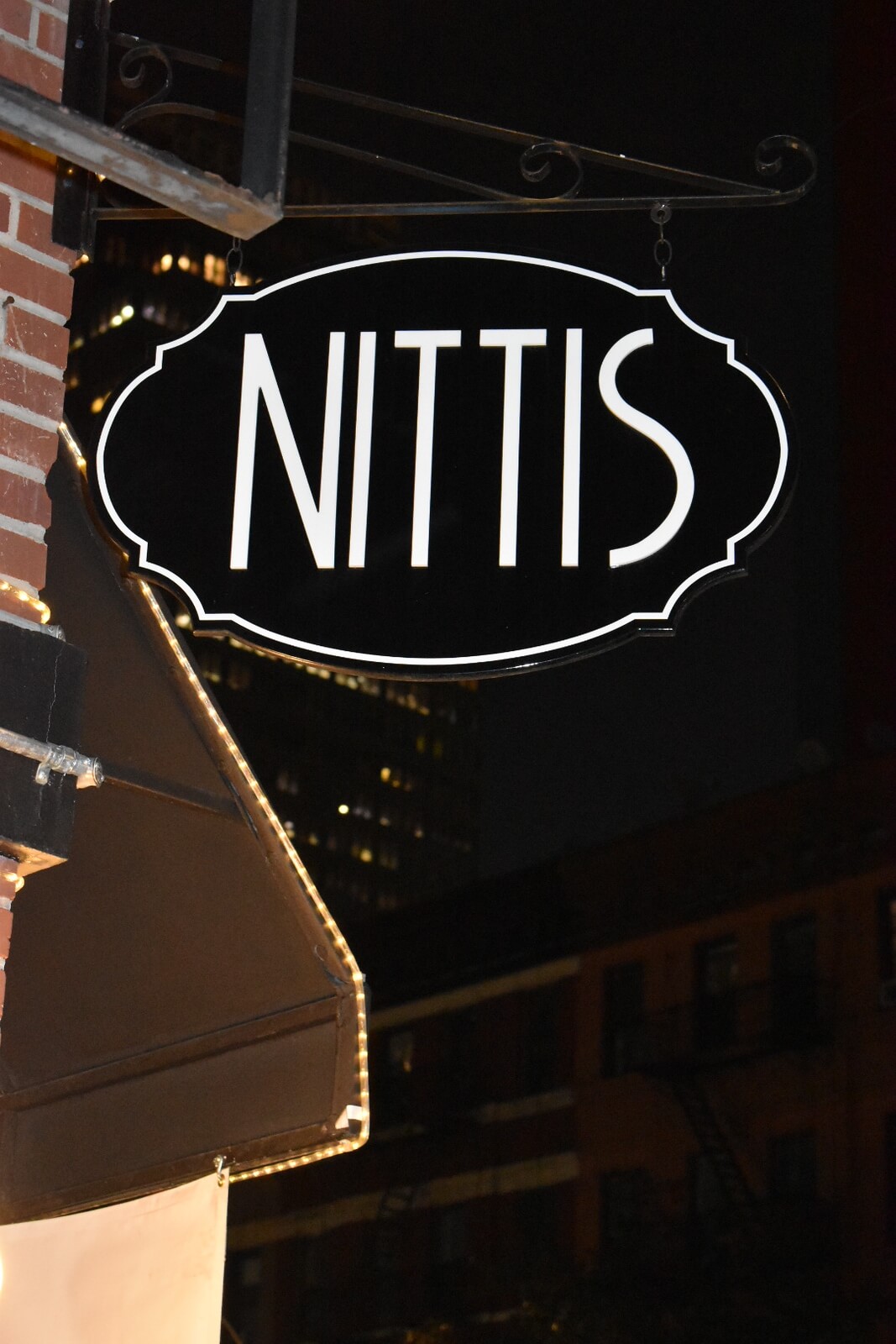 Black street sign with 'Nittis' written in white