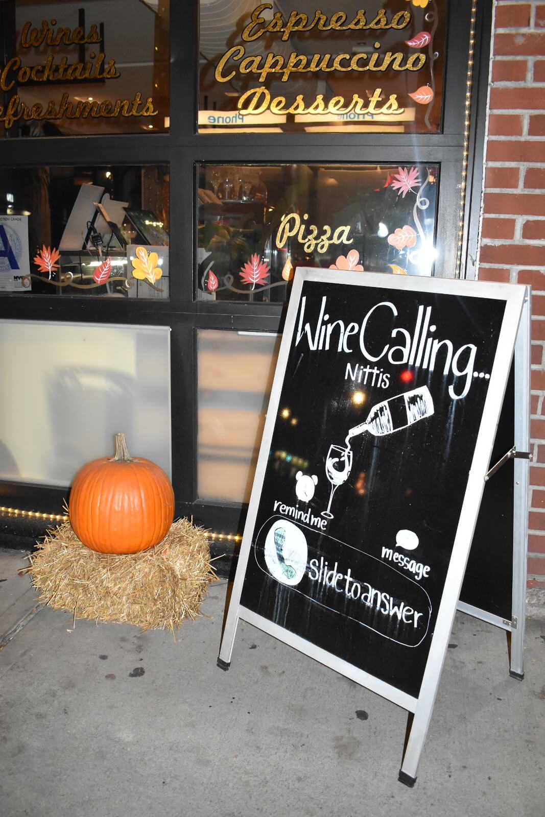 Sidewalk sign with a picture of wine poured into a glass that says 'Wine Calling'