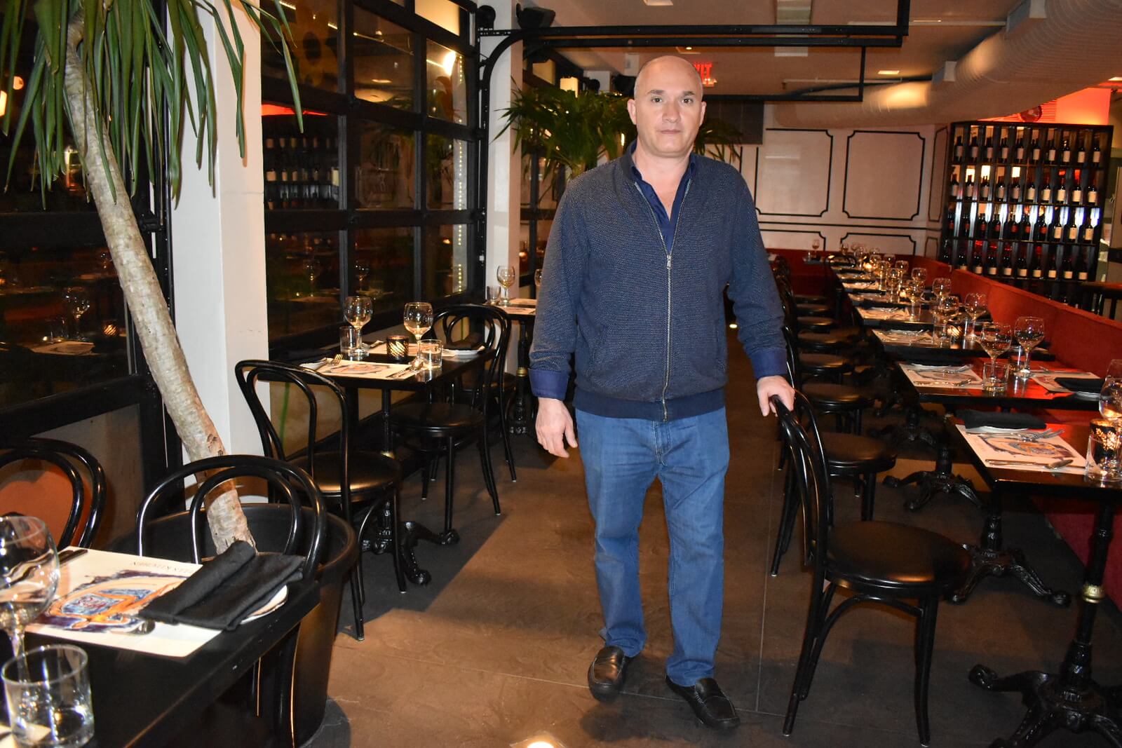 Man standing in restaurant with rows of tables and chairs on either side